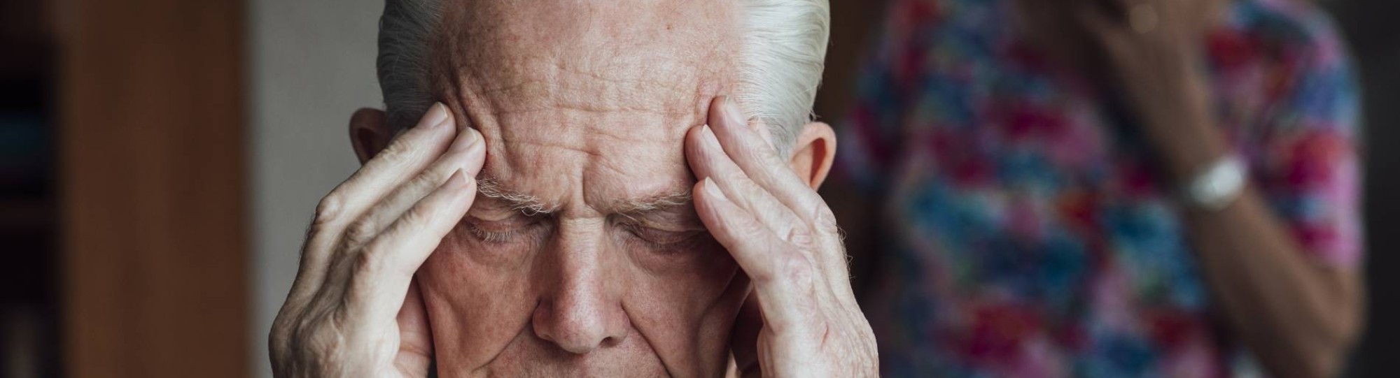Oudere met dementie grijpt naar zijn hoofd