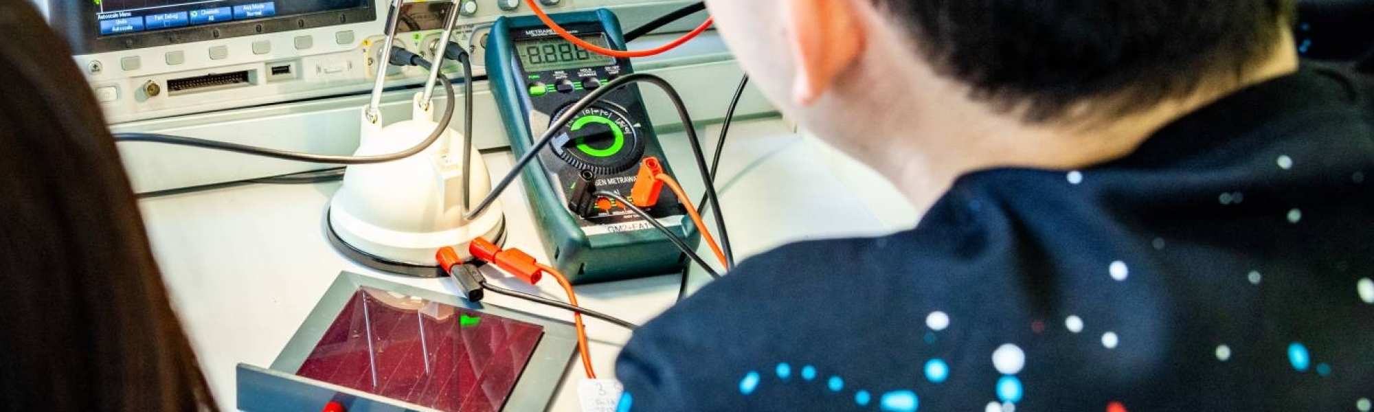 Twee studenten elektrotechniek doen een experiment met een zonnepaneel.