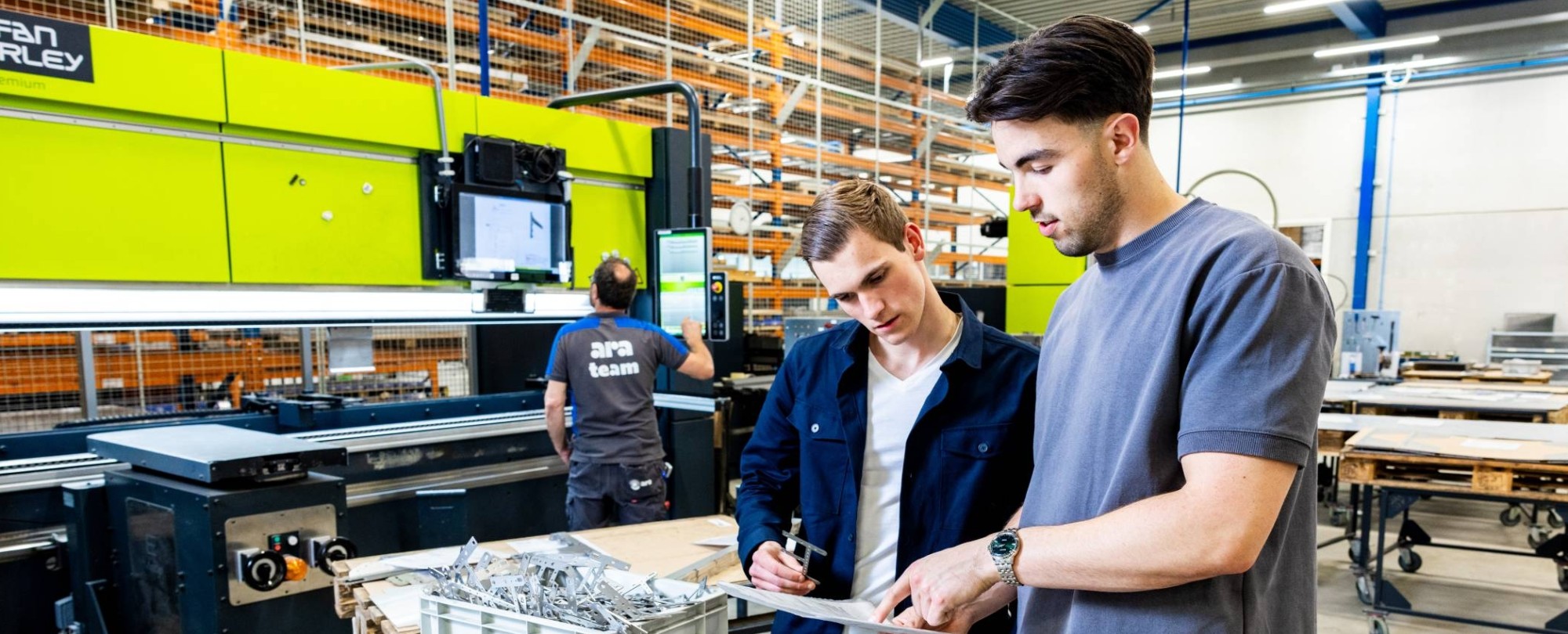 Twee studenten Technische Bedrijfskunde overleggen op de werkvloer van ARA.