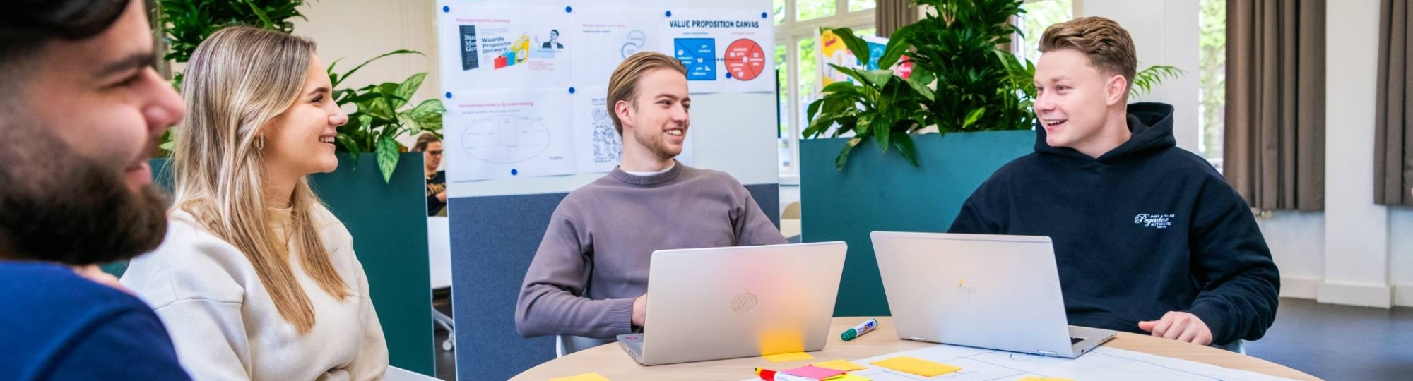 Een groep studenten aan tafel met laptops