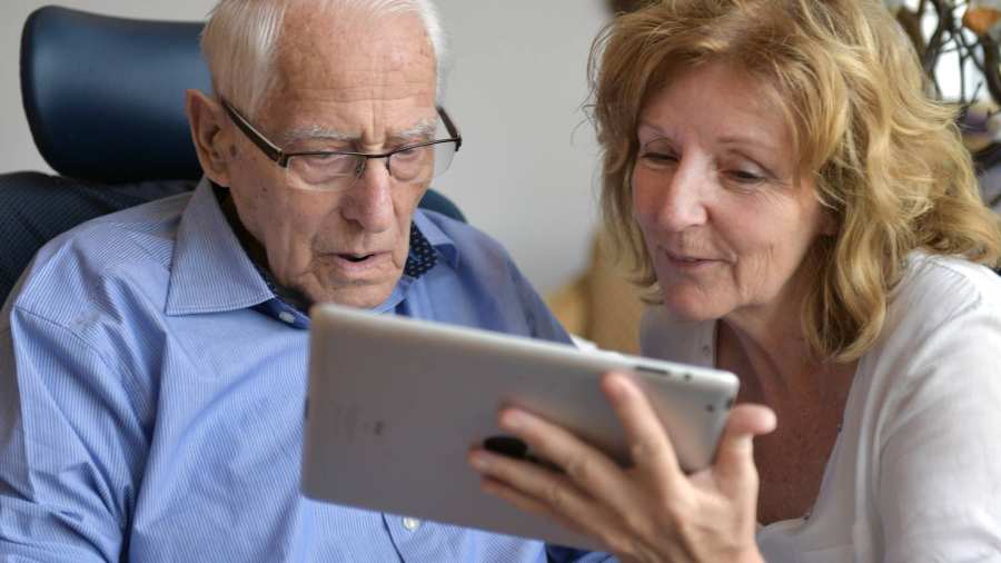 toont fotoâs op een tablet aan een bewoner van het verpleeghuis