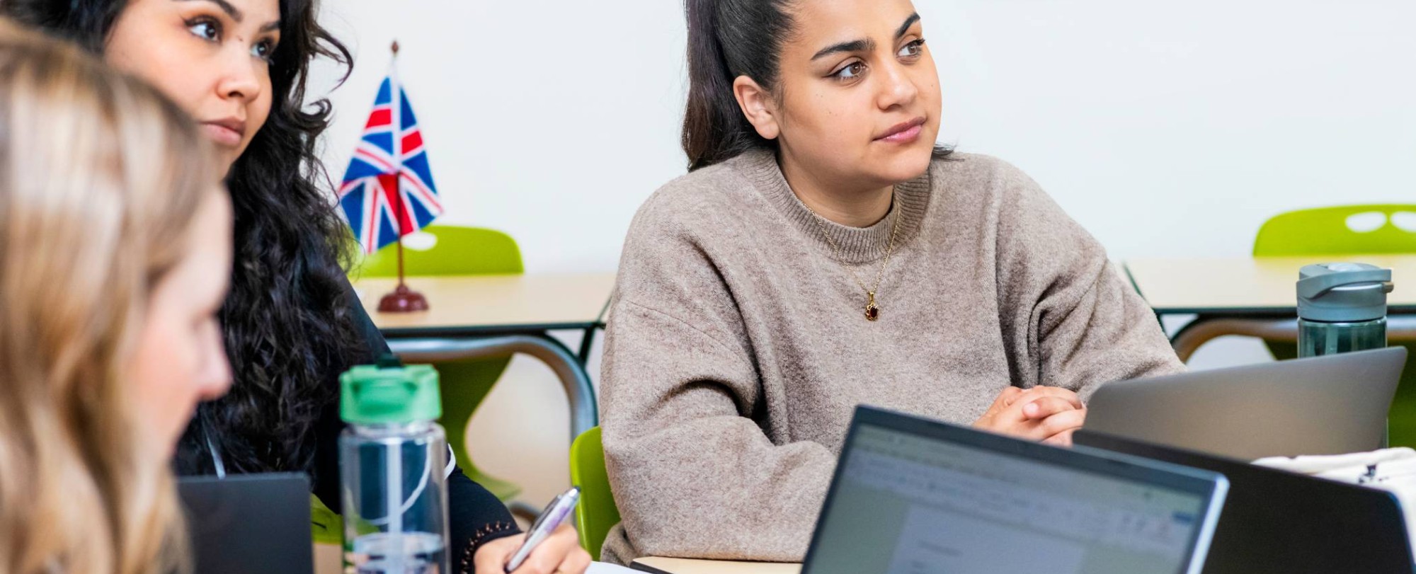 Twee studenten kijken al luisterend naar de docent.
