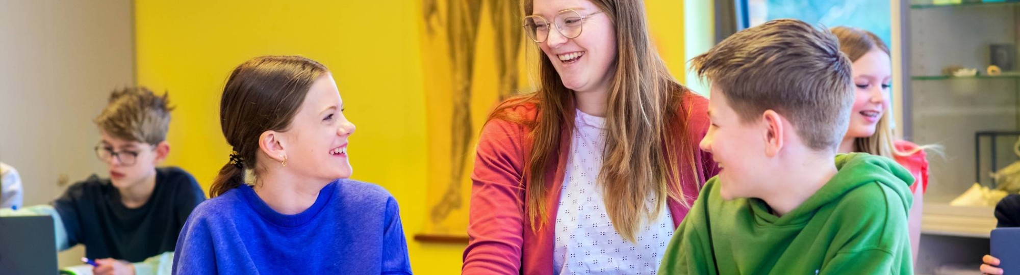 Fotoshoot op het Citadel 2024. De docente lacht met 2 scholieren in de klas. 