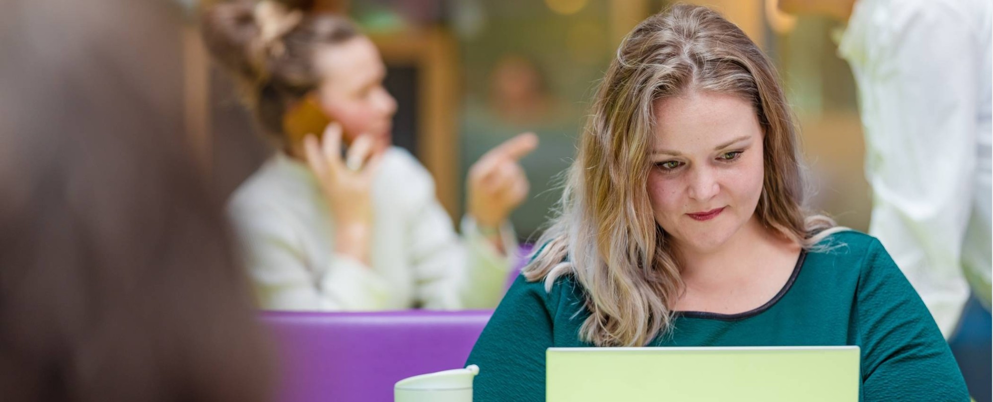 Een student van de module Interventiekunde zit achter haar laptop in de hal van de HAN-campus