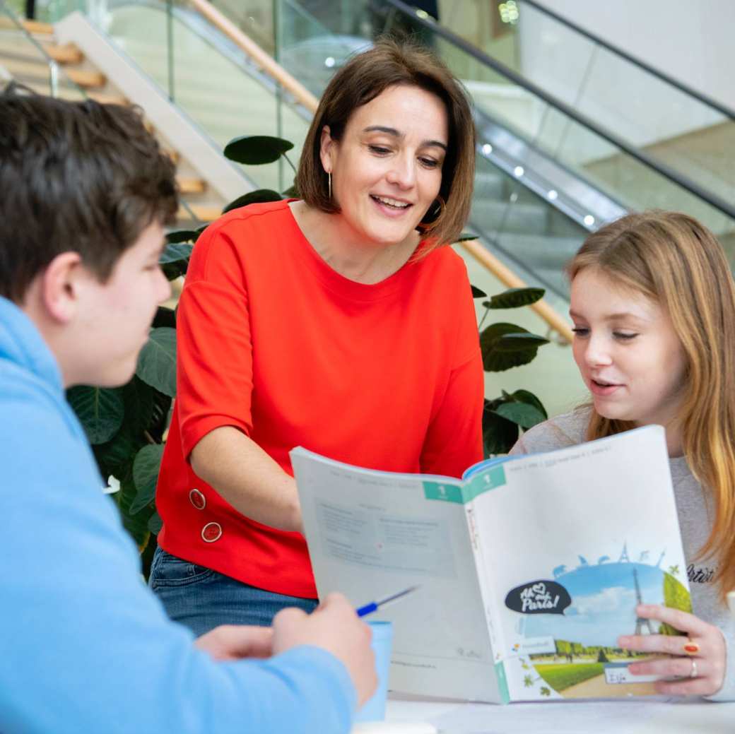 Twee studenten werken samen achter de laptop in het I/O gebouw en kijken lachend naar het scherm.