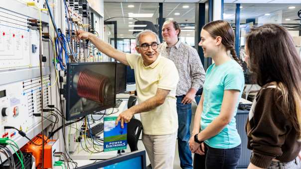 Een docent elektrotechniek geeft uitleg aan studenten in het hoogspanningslab.