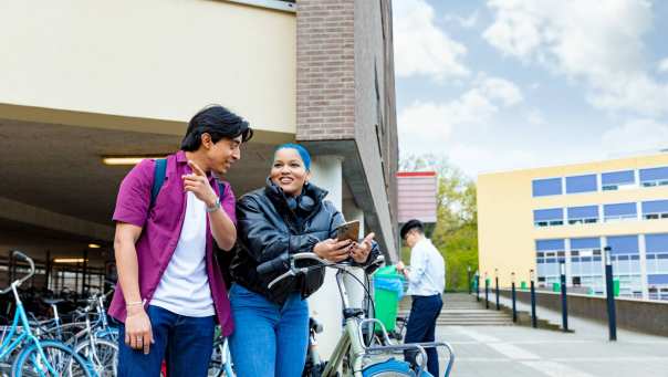 International students Diego and Chadionne with their bikes looking for directions on the Arnhem campus of HAN University of Applied Sciences.