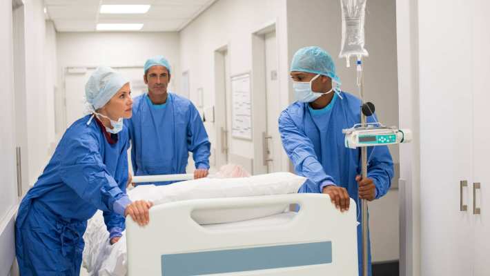 Ziekenhuispersoneel in ziekenhuis duwen een bed met patient