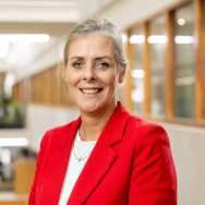 Portretfoto Leslie Michielsen, wit shirt met rood jasje dragend. Haren vast