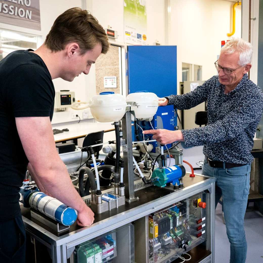 Automotive student krijgt uitleg van een docent bij de waterstoftafel.