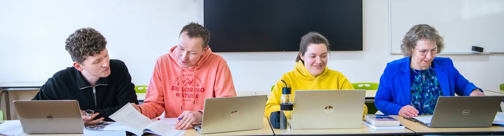 4 masterstudenten op een rij met laptops voor zich die bezig zijn zich aan te melden
