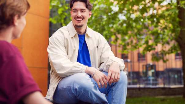 werving voltijd campagne, student met sikje zit op een picnictafel in de binnentuin.