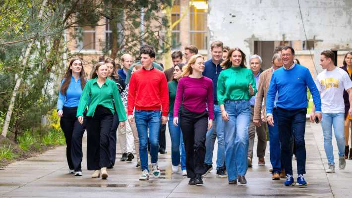 Groep studenten en docenten wandelt door IPKW met groen op de achtergrond. Fotografie Master Circulaire Economie voltijd.