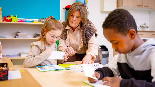 Speciaal Onderwijs op de school Lichtenbeek. De lerares kijkt mee bij een leerling in een boekje. 