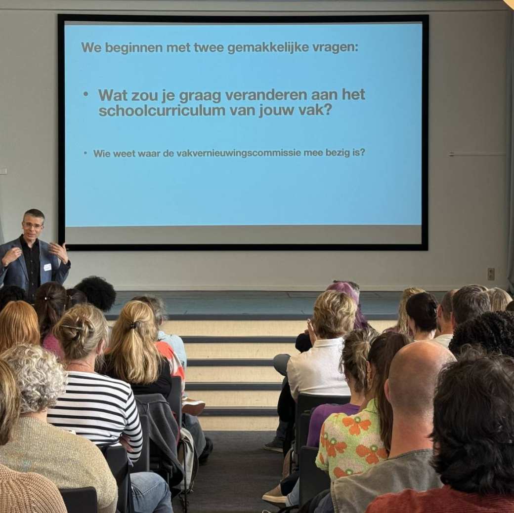 Sebastiaan Dönszelmann die een vraag stelt aan de groep bij het symposium