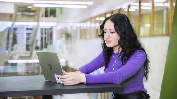 Een student werkt achter haar laptop.