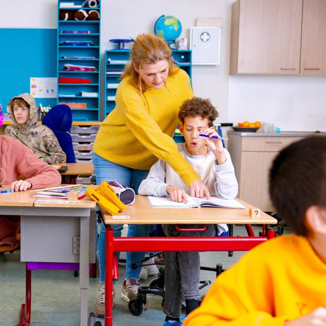 Speciaal Onderwijs op de school Lichtenbeek. De lerares wijst in een boekje van de leerling iets aan. 