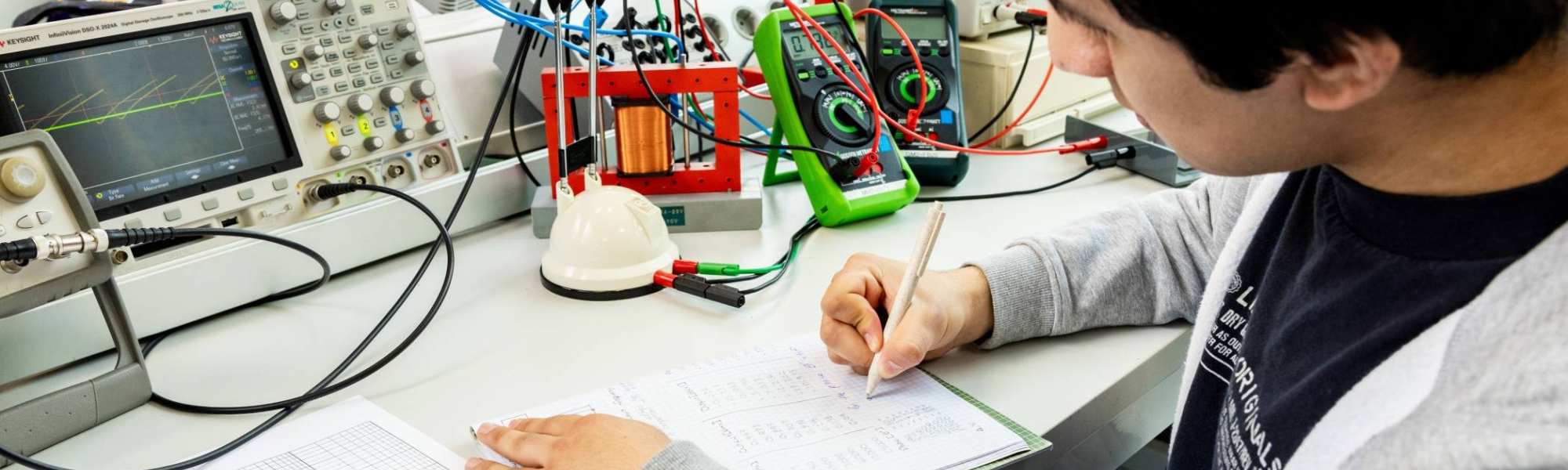 Een student elektrotechniek werkt aan een logboek tijdens het netwerkpracticum.