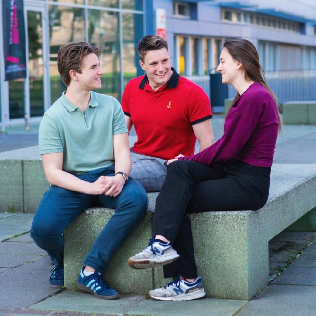 Studenten hbo Bedrijfskunde zitten op een bankje op de HAN Campus Nijmegen