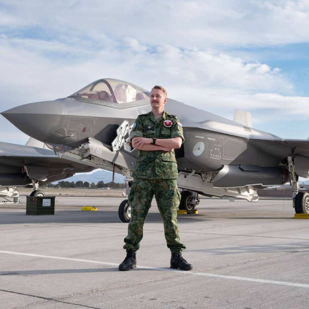 Student Bram Wieser van de opleiding Bedrijfskunde deeltijd. Bram draagt een uniform van de luchtmacht en staat voor een vliegtuig van Defensie.