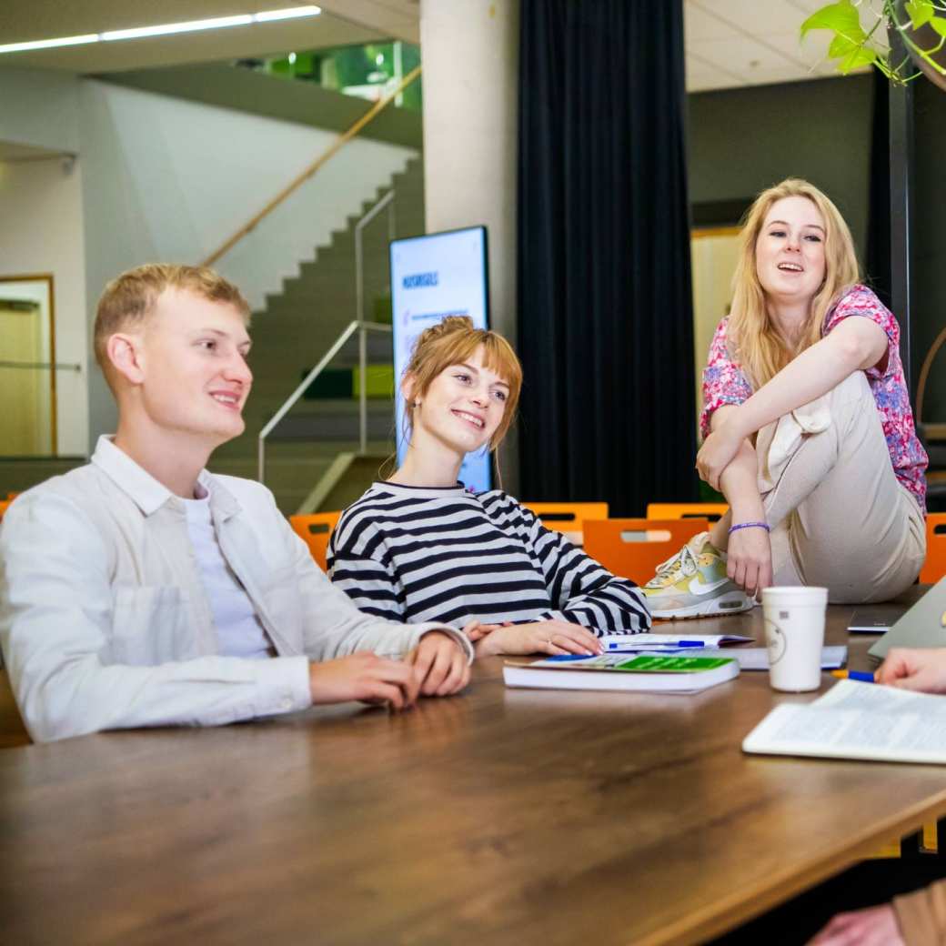 5 Leraar Geschiedenis studenten staan rondom een tafel om een kaartspel te doen.