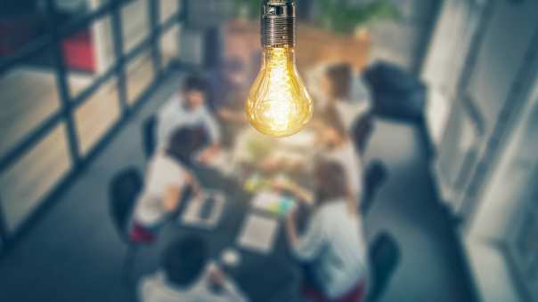 Peertje (lamp) dat hangt boven een tafel waaraan mensen zitten. Lamp scherp, mensen vaag. Stockfoto