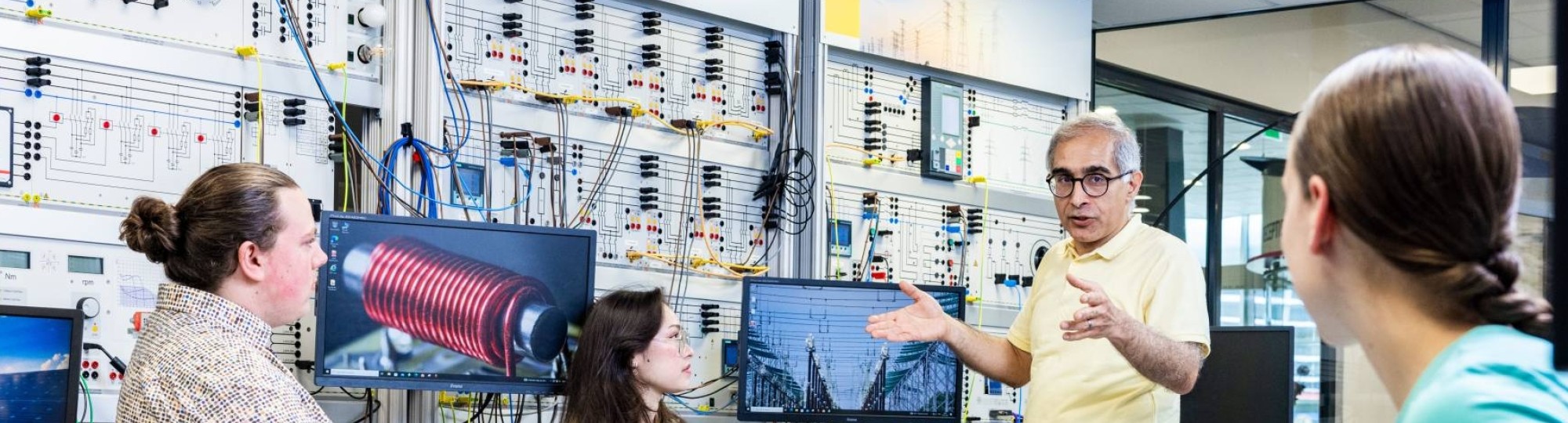 Studenten en docent elektrotechniek tijdens een les in het hoogspanningslab.