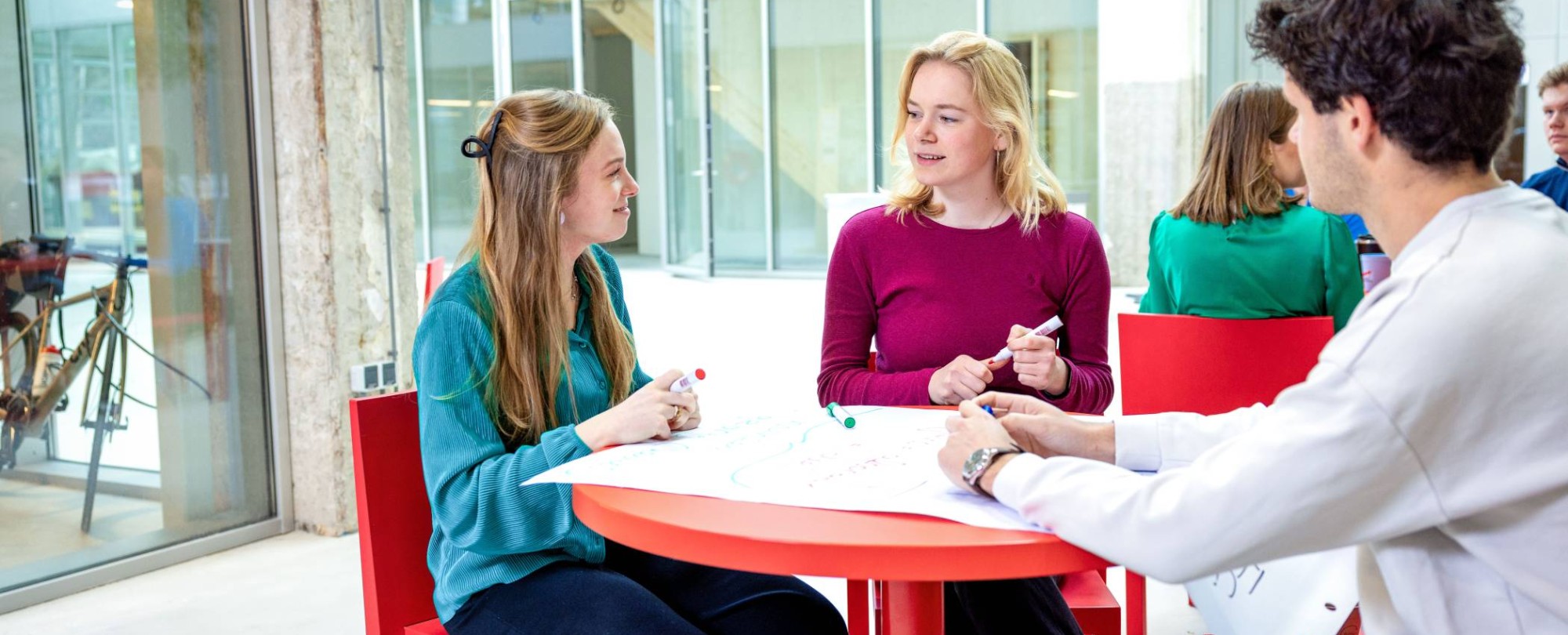 Lachende studenten aan tafel. Master Circulaire Economie 2024.