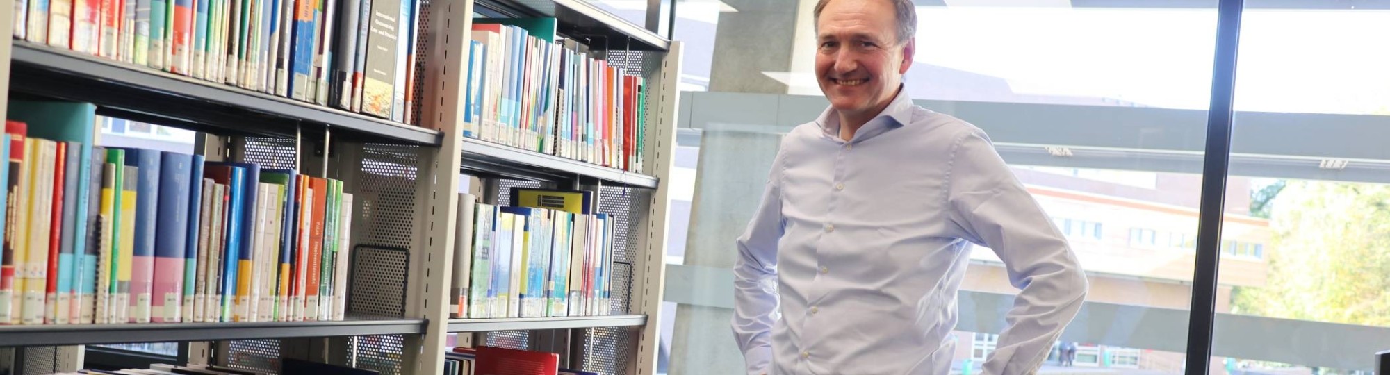 Docent-onderzoeker Ger Sluman staand voor boekenkast in het studiecentrum op Ruitenberglaan 31, na een interview over zijn onderzoek.
