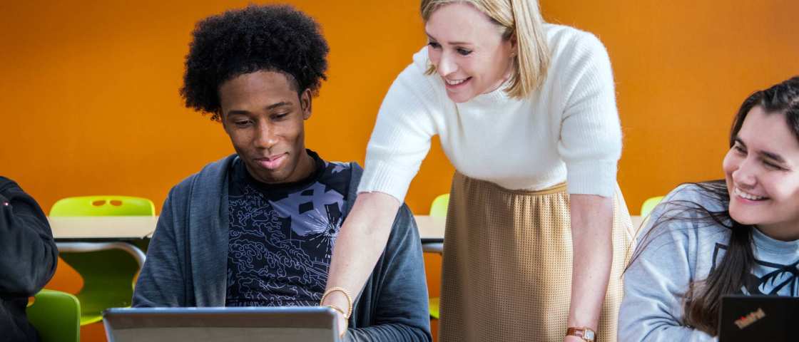 docent legt 2 masterstudenten wat uit en wijst op de laptop