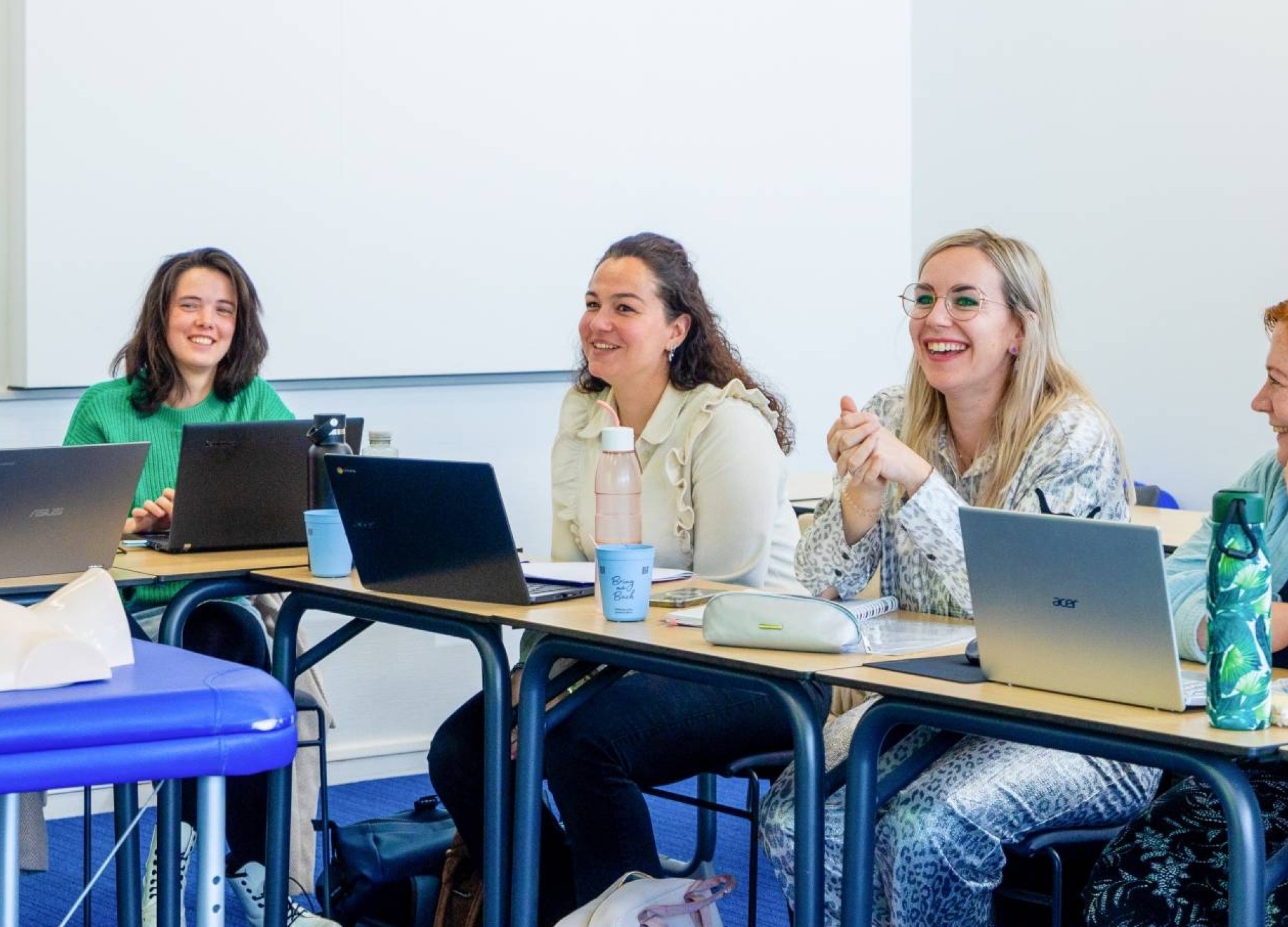 Vijf studenten zijn aan het lachen tijdens praktijkles technische thuiszorgverpleegkundige. 