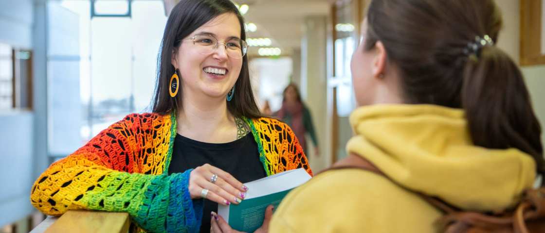 2 masterstudenten staan op de gang met één boek in de hand