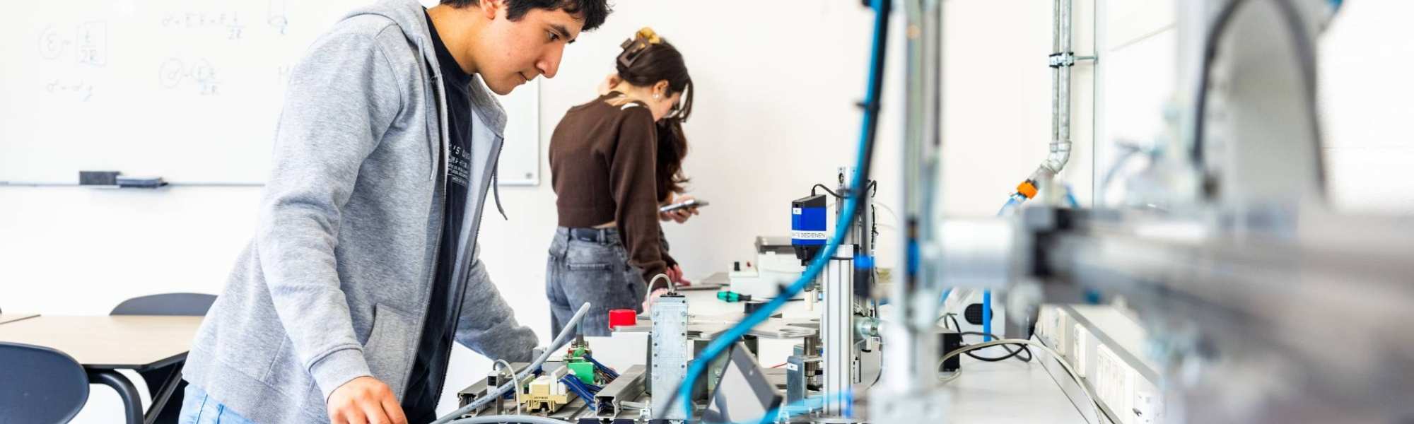 Elektrotechniekstudent Juan werkt aan een PLC in een practicumruimte.