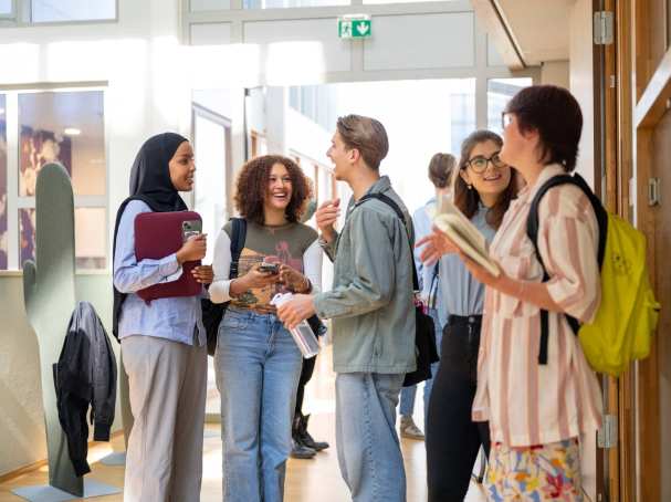 Een groepje studenten staan te wachten voor de klas en hebben plezier. 