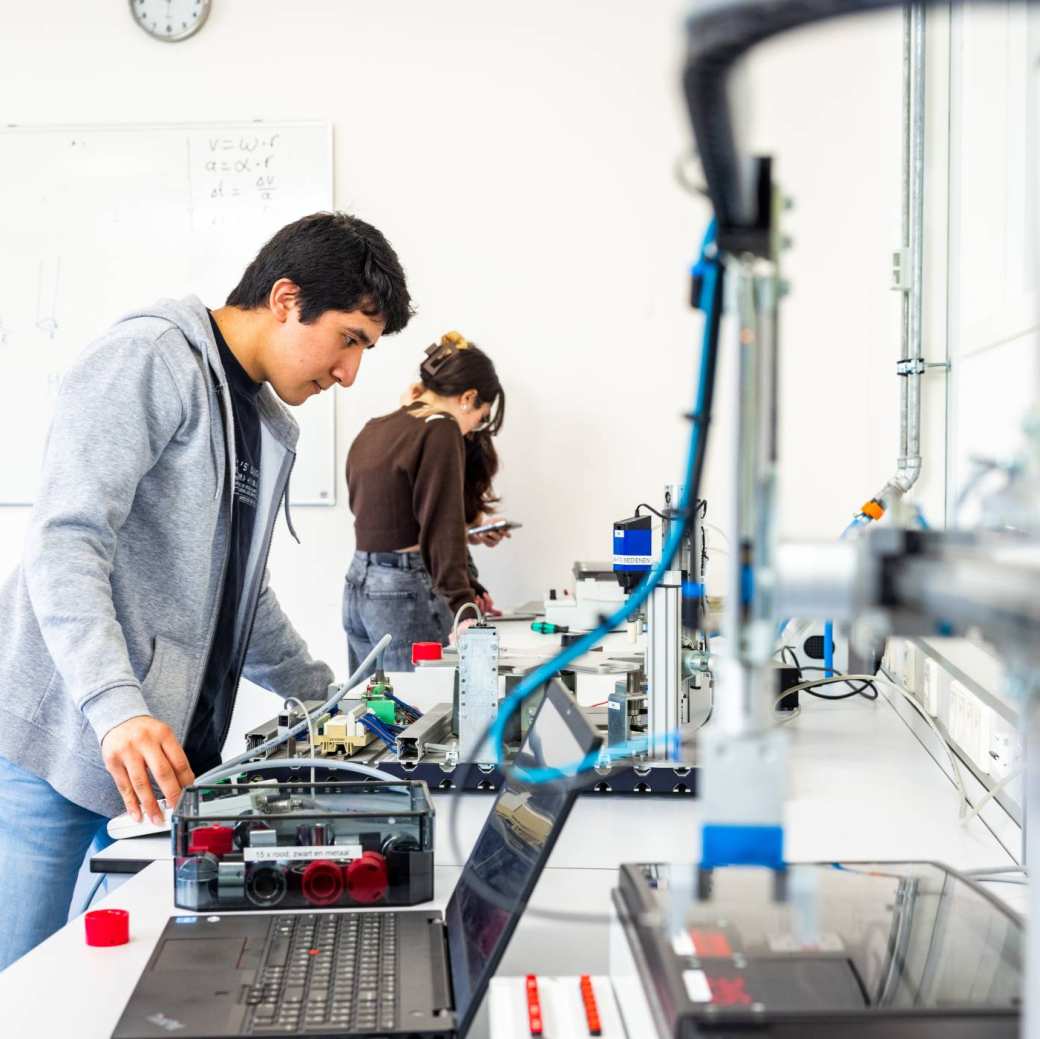 Elektrotechniekstudent Juan werkt aan een PLC in een practicumruimte.