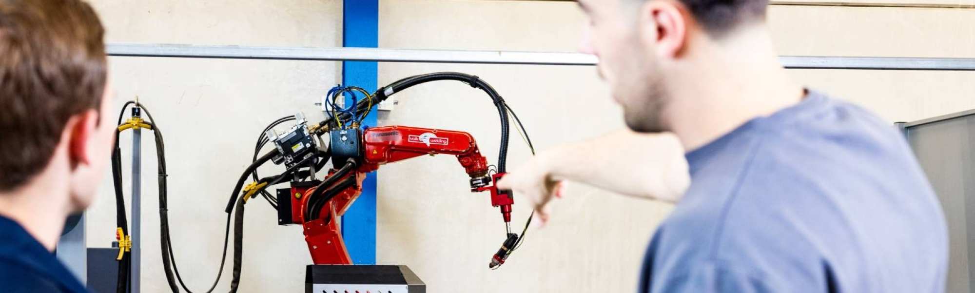 Technische Bedrijfskunde studenten Jort en Derk samen bij robot arm.