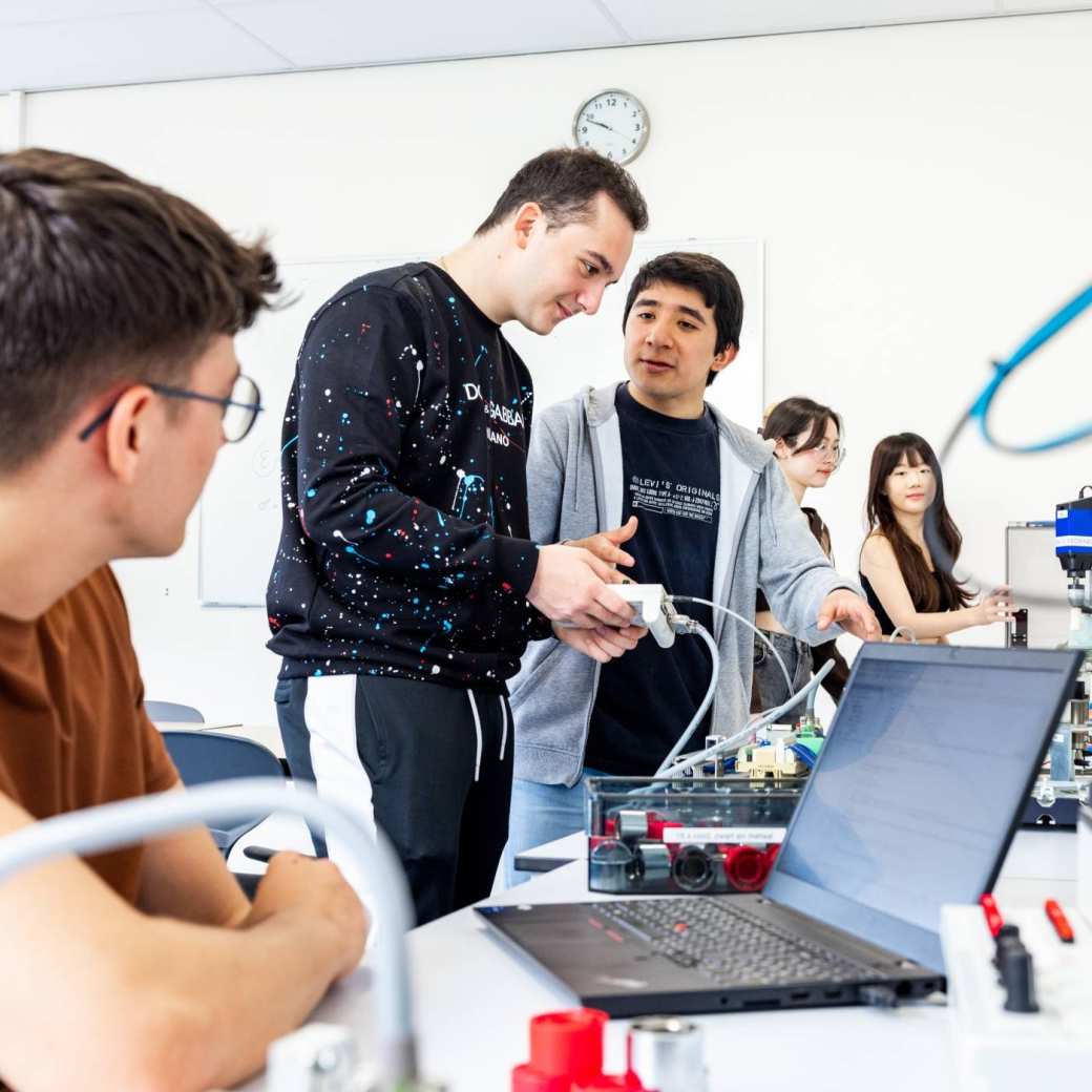 Drie elektrotechniekstudenten werken samen aan een PLC.