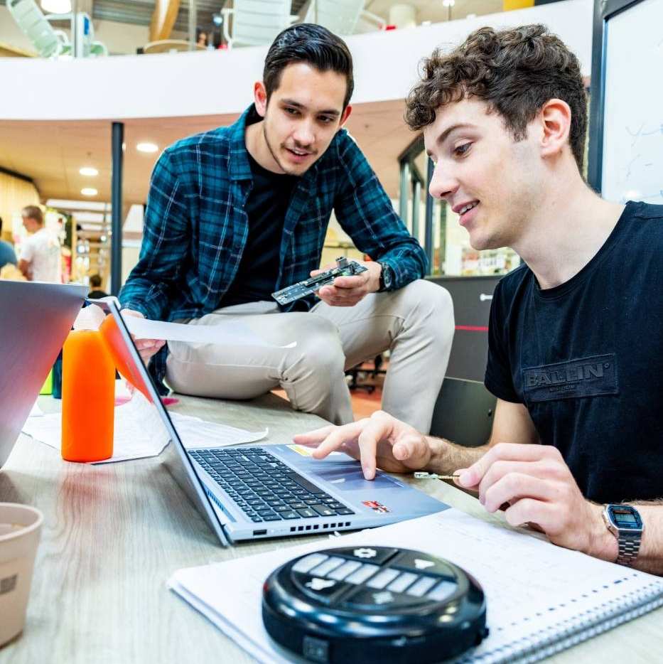 Twee studenten embedded systems engineering werken samen op de laptop.