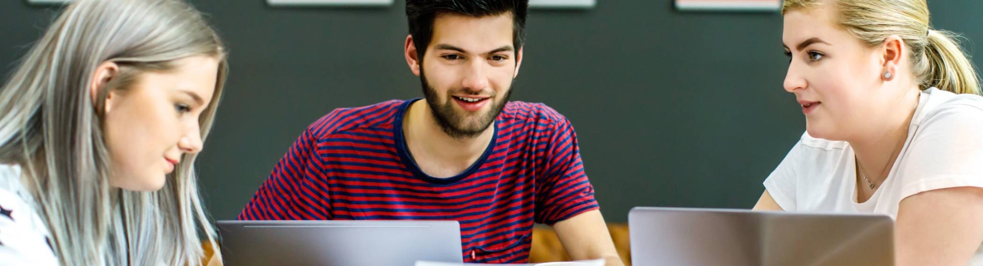 Twee studenten kijken naar wat hun medestudent aanwijst op het A4'tje. 