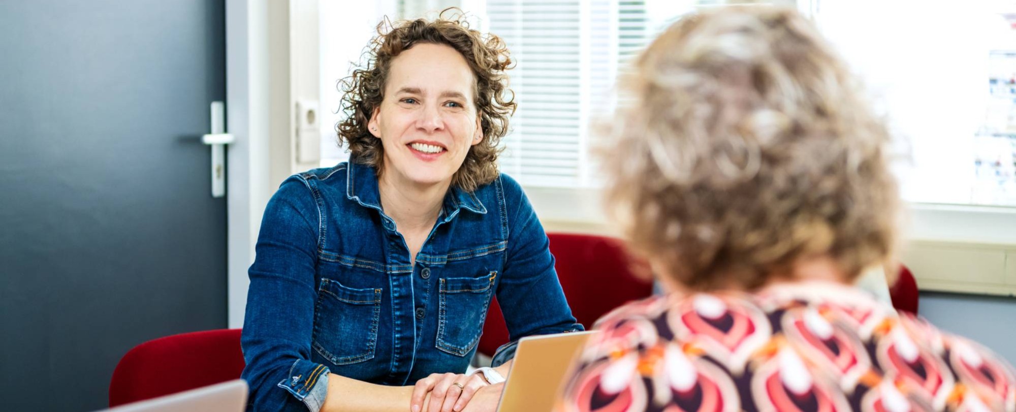 2 docenten zitten aan tafel in overleg