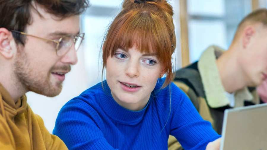 Twee studenten zitten in de mediatheek en kijken geconcentreerd naar de laptop.