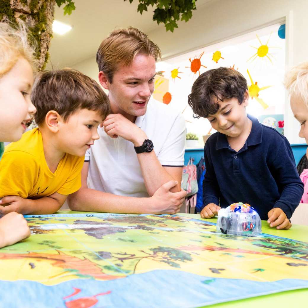 Pabo-ALO docent luistert naar haar drie studenten die aan de tafel zitten te overleggen.