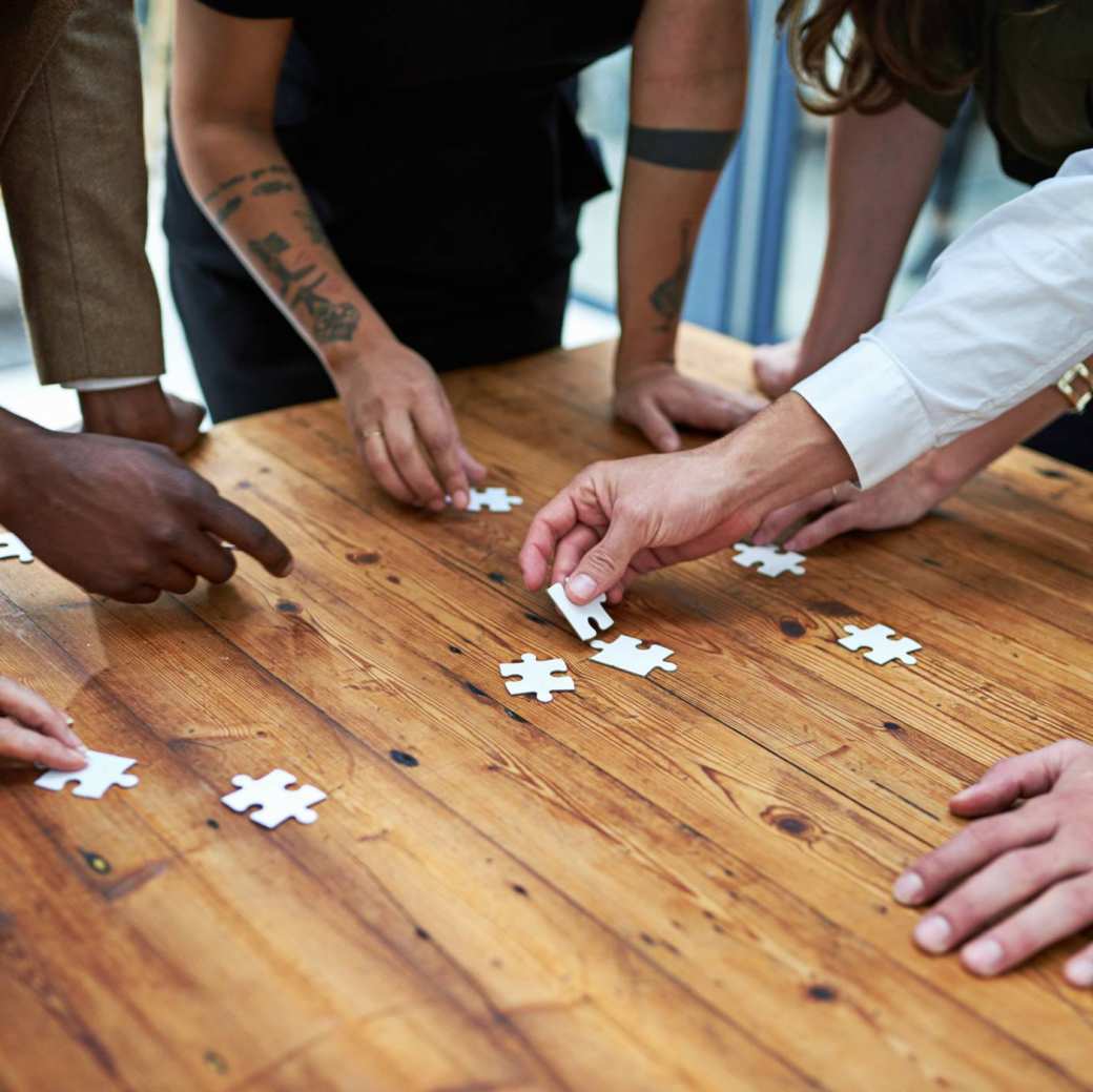 Op een vierkante houten tafel samen een puzzel leggen. Puzzelstukjes, samenwerken, seece