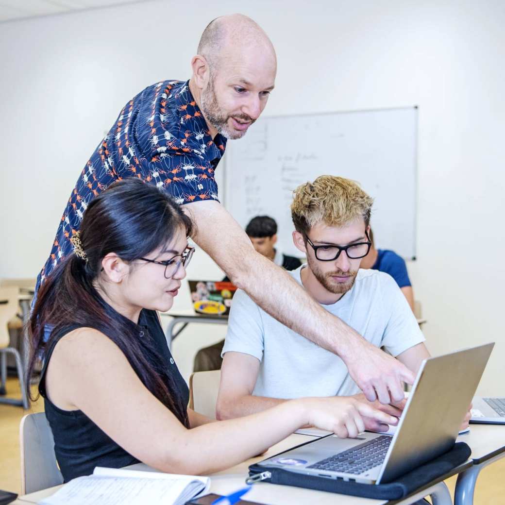 Medische Hulpverlening docent legt theorie uit aan twee studentes op een laptop