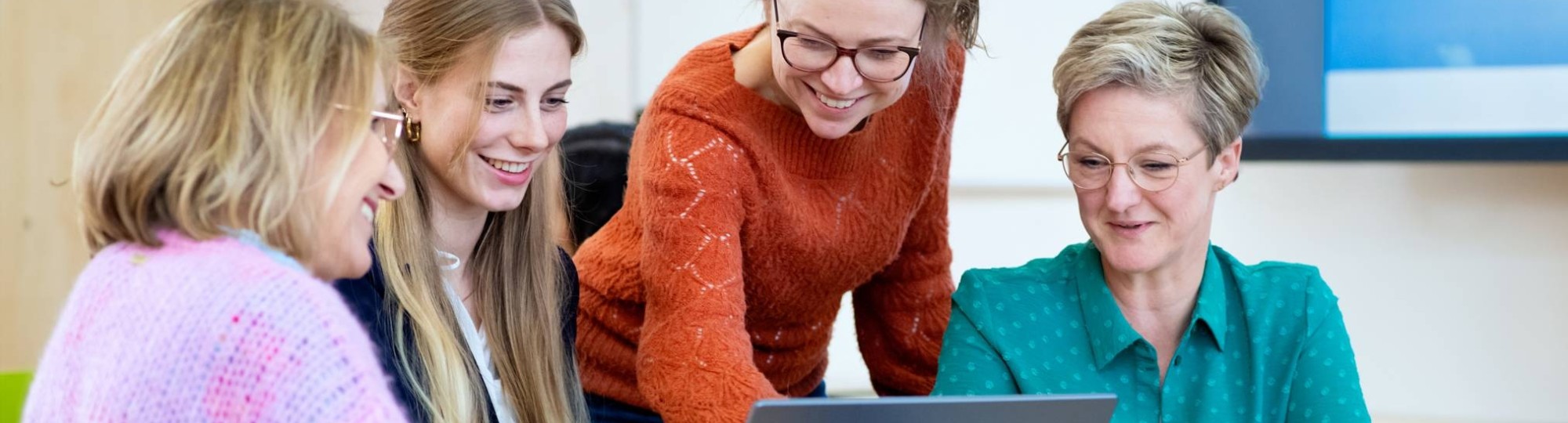 Vier studenten kijken samen naar het scherm (laptop). 