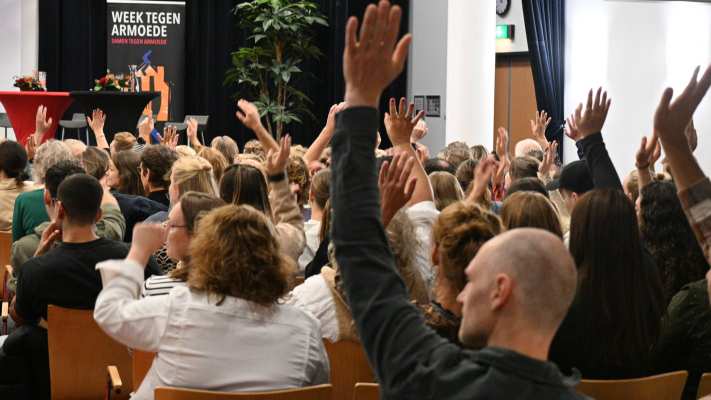 publiek met handen omhoog tijdens symposium beyond borders week tegen armoede 