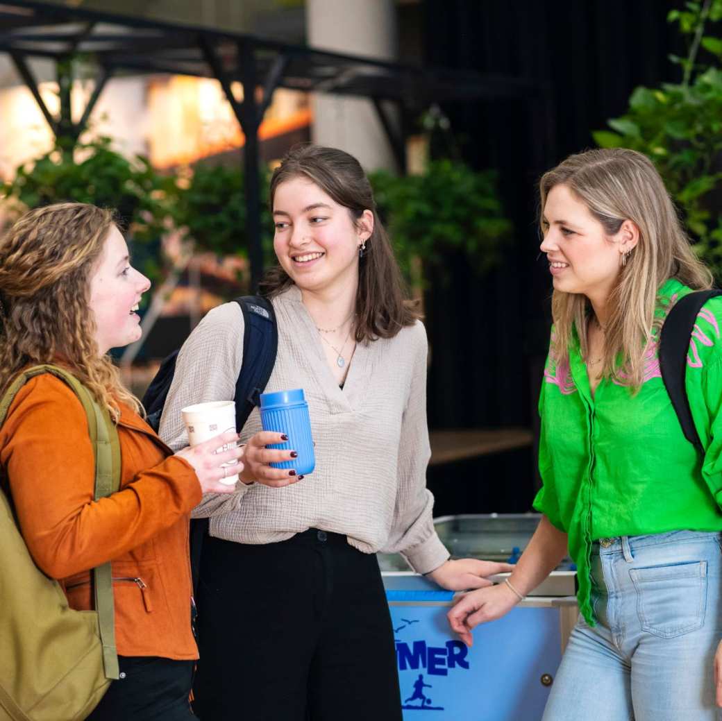 Vier studenten van Leraar Aardrijkskunde zitten op de bank en bladeren door de atlas.