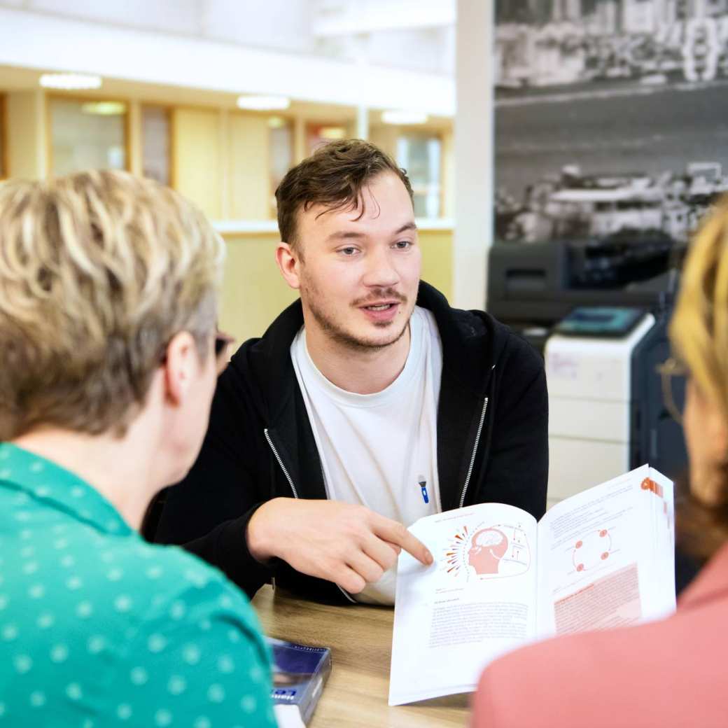 Student wijst een plaatje aan in het boek. Het plaatje is een hoofd.