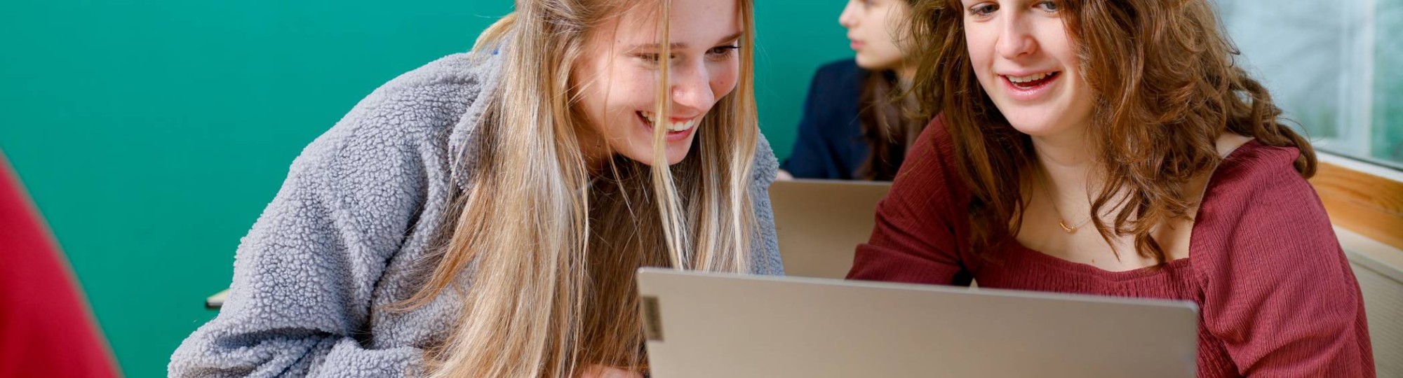 Studenten kijken lachend naar een iPad