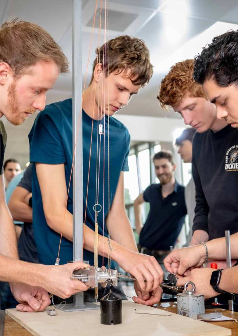 Vier studenten werktuigbouwkunde doen tests met een katrol en gewichten.